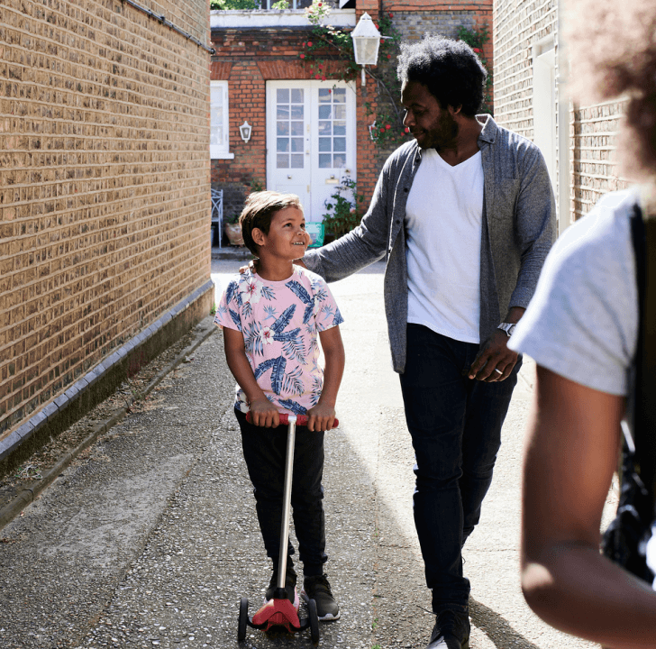 a father and daughter walking together in an alleyway.