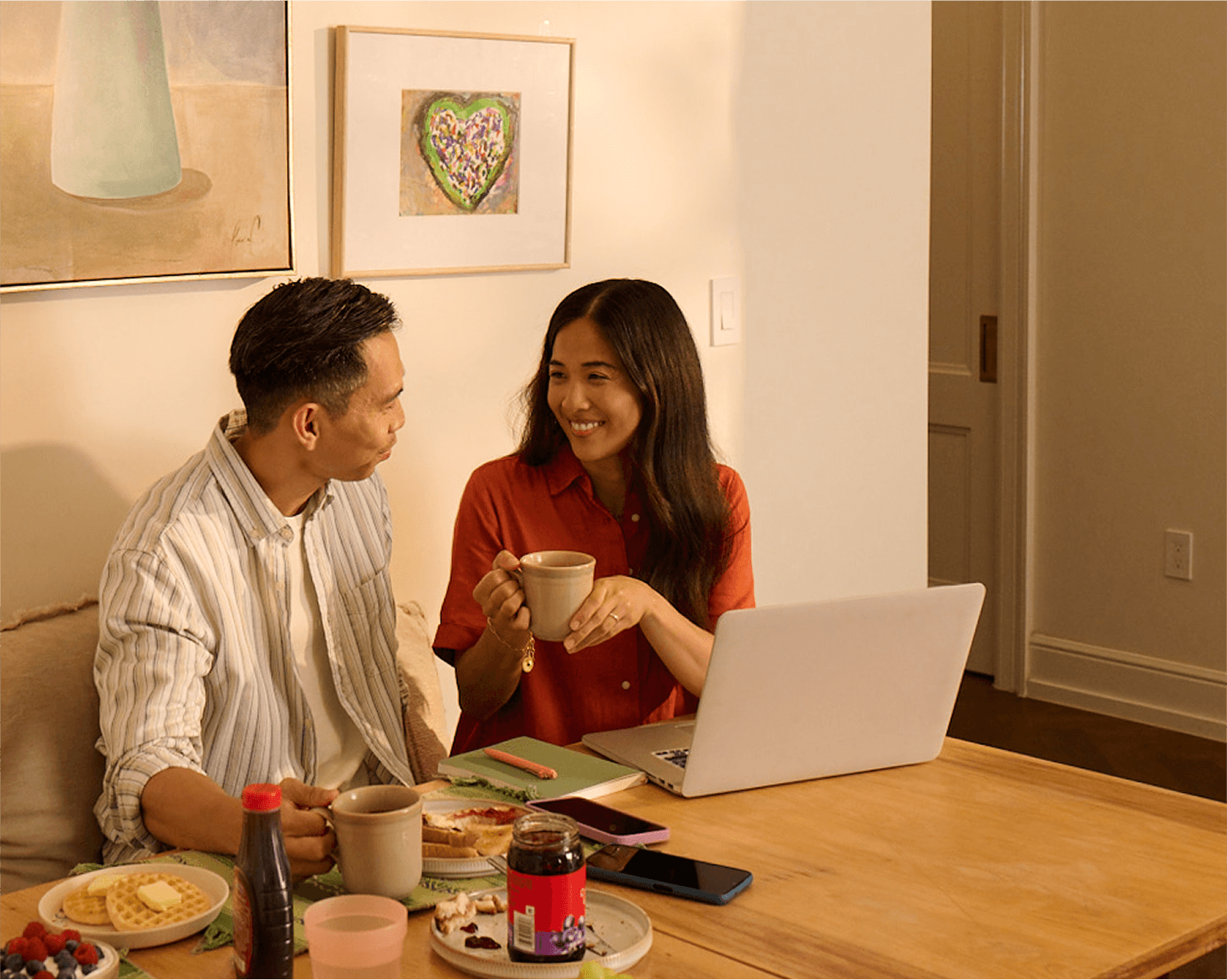 Couple smiling while looking at a laptop at home